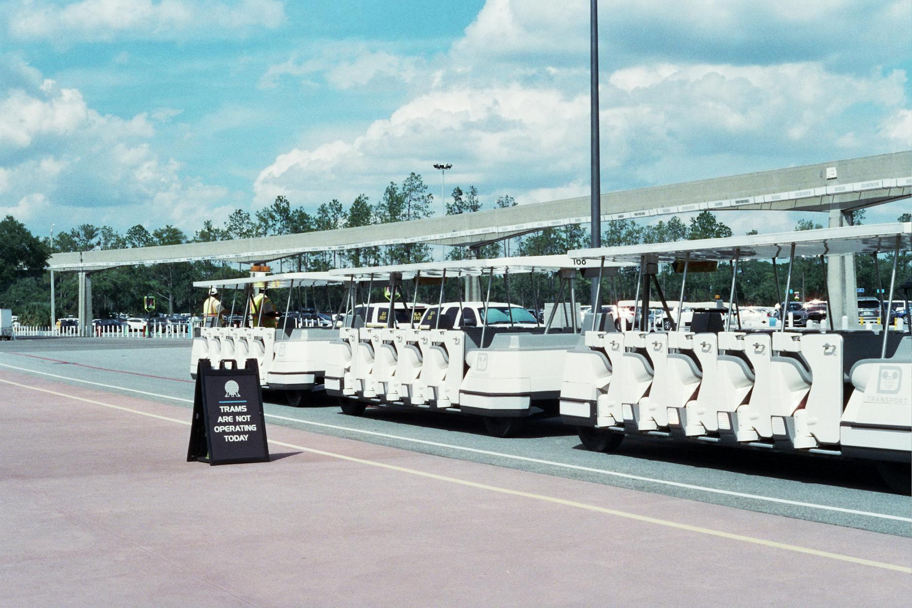 open-air tram shuttling visitors across a large theme park parking lot