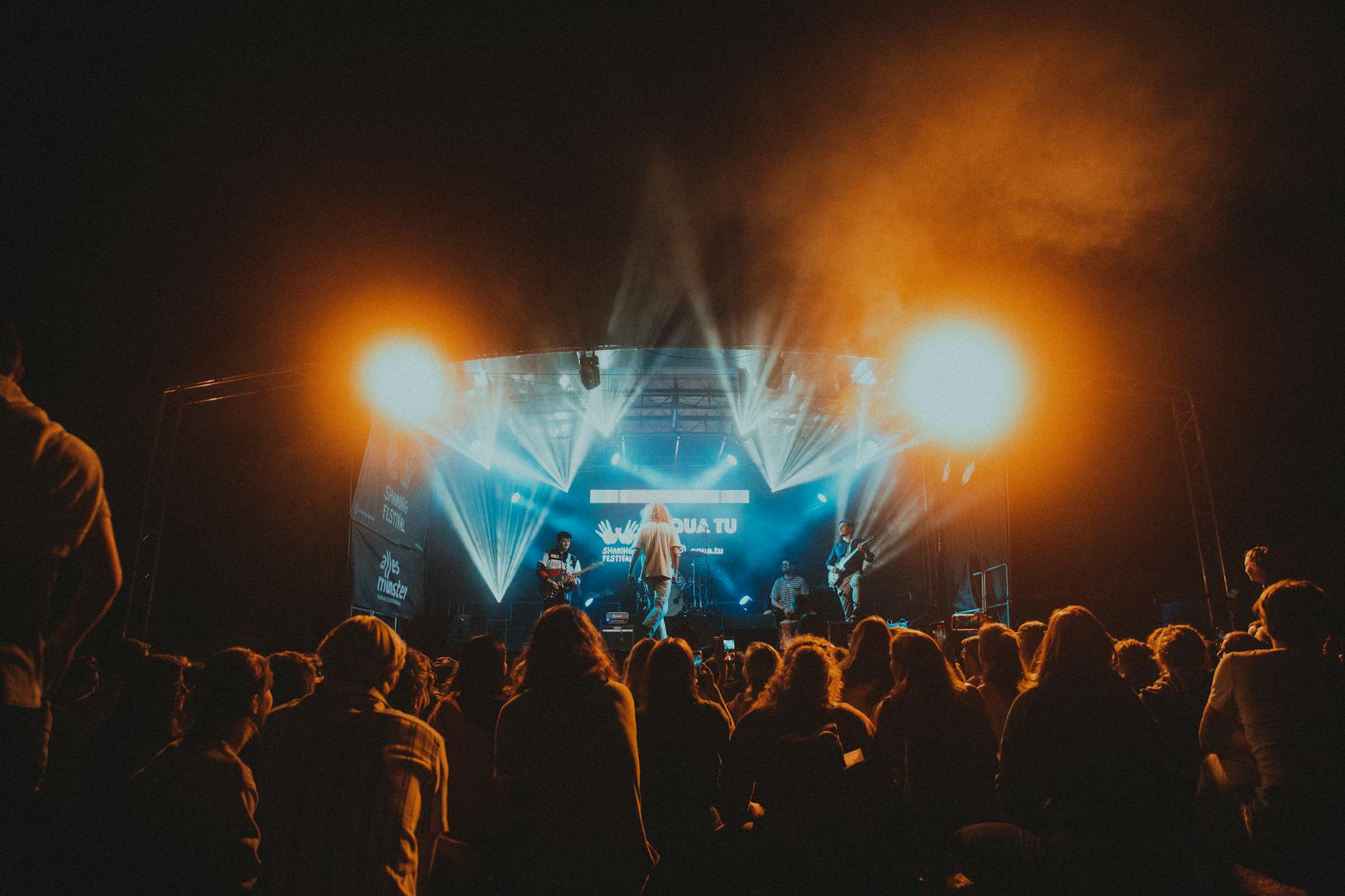Outdoor live music concert with band performing on stage and audience watching