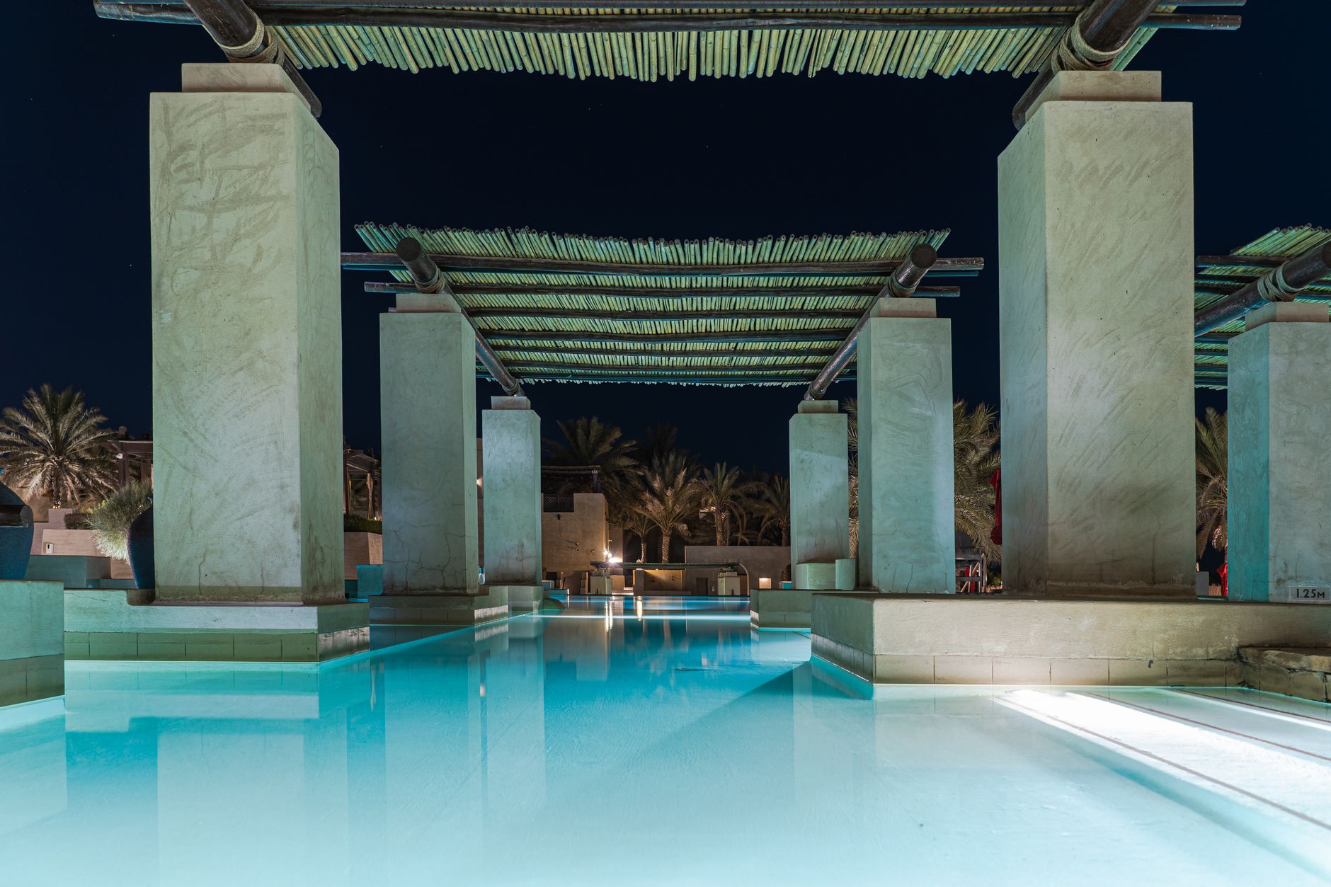 Resort pool night palm trees lit underwater