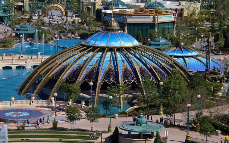 The blue and gold glass domes of the Constellation Carousel beside the fountains of Celestial Park at Epic Universe