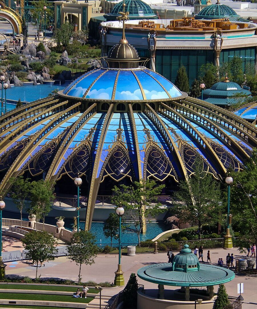 The blue and gold glass domes of the Constellation Carousel beside the fountains of Celestial Park at Epic Universe