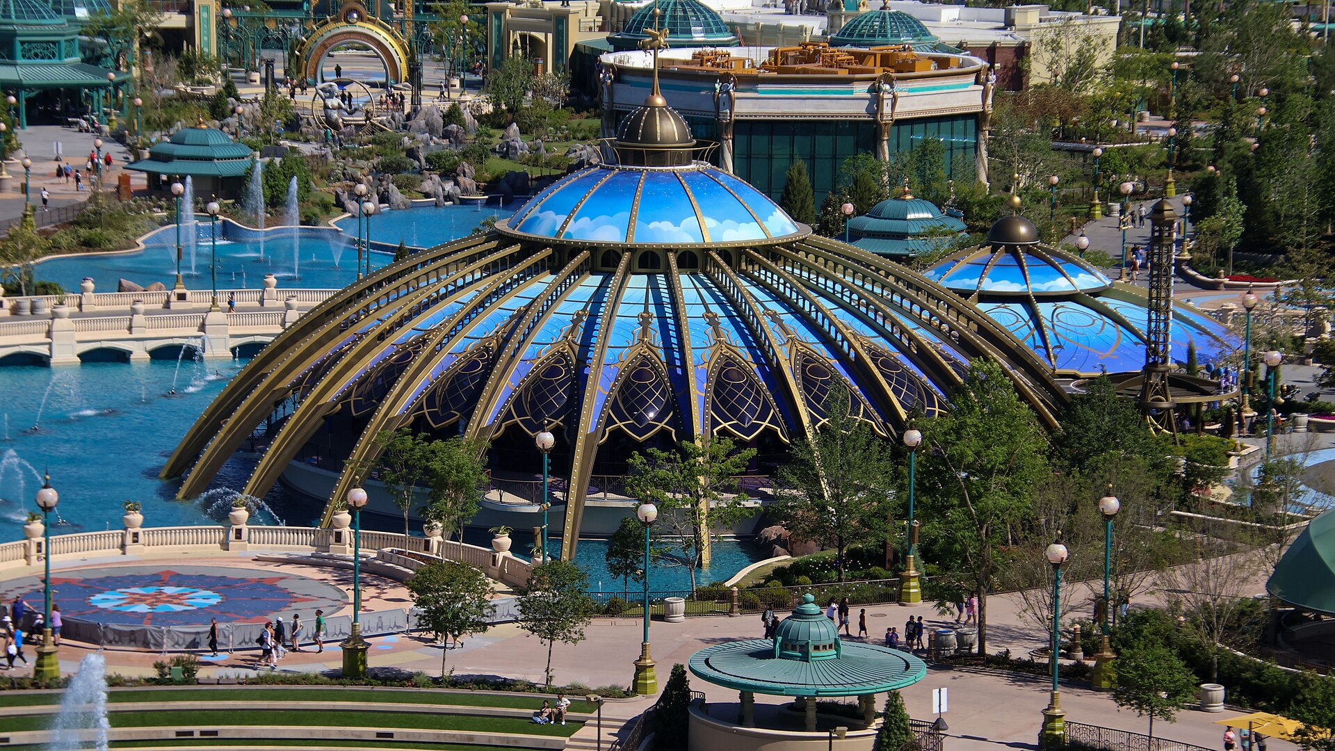 The blue and gold glass domes of the Constellation Carousel beside the fountains of Celestial Park at Epic Universe