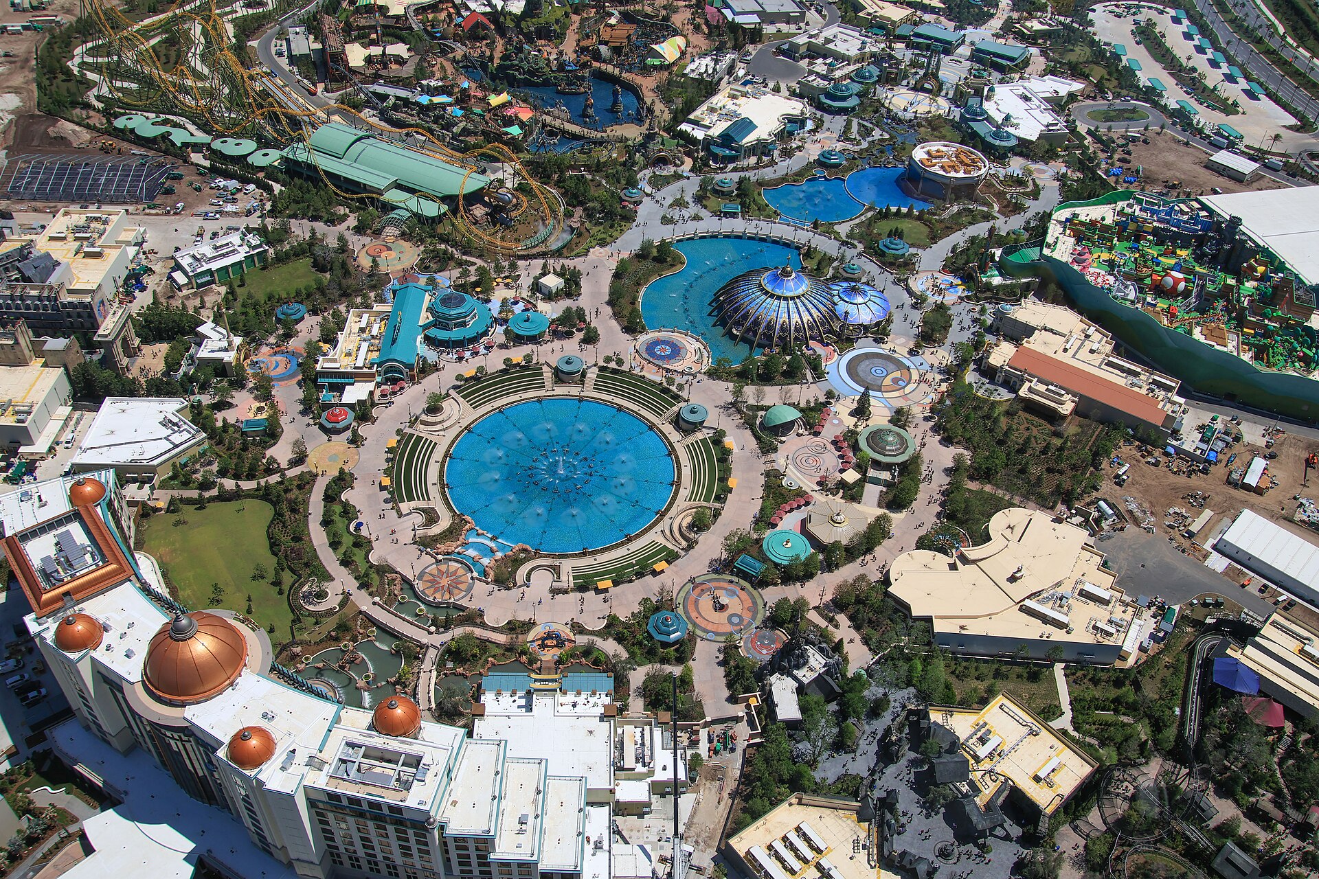 Aerial view of Celestial Park at Epic Universe showing the circular fountain, the Constellation Carousel domes and the surrounding lands