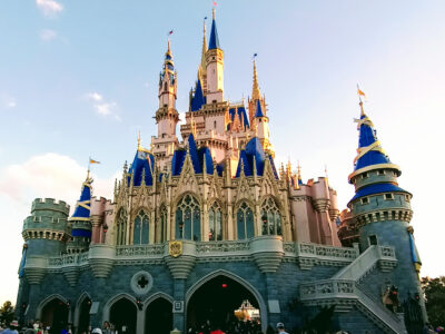 Cinderella Castle at Magic Kingdom in its pink, blue and gold paint scheme with guests below