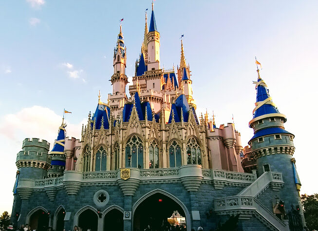 Cinderella Castle at Magic Kingdom in its pink, blue and gold paint scheme with guests below