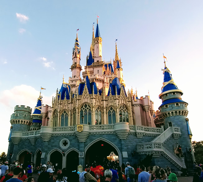 Cinderella Castle at Magic Kingdom in its pink, blue and gold paint scheme with guests below