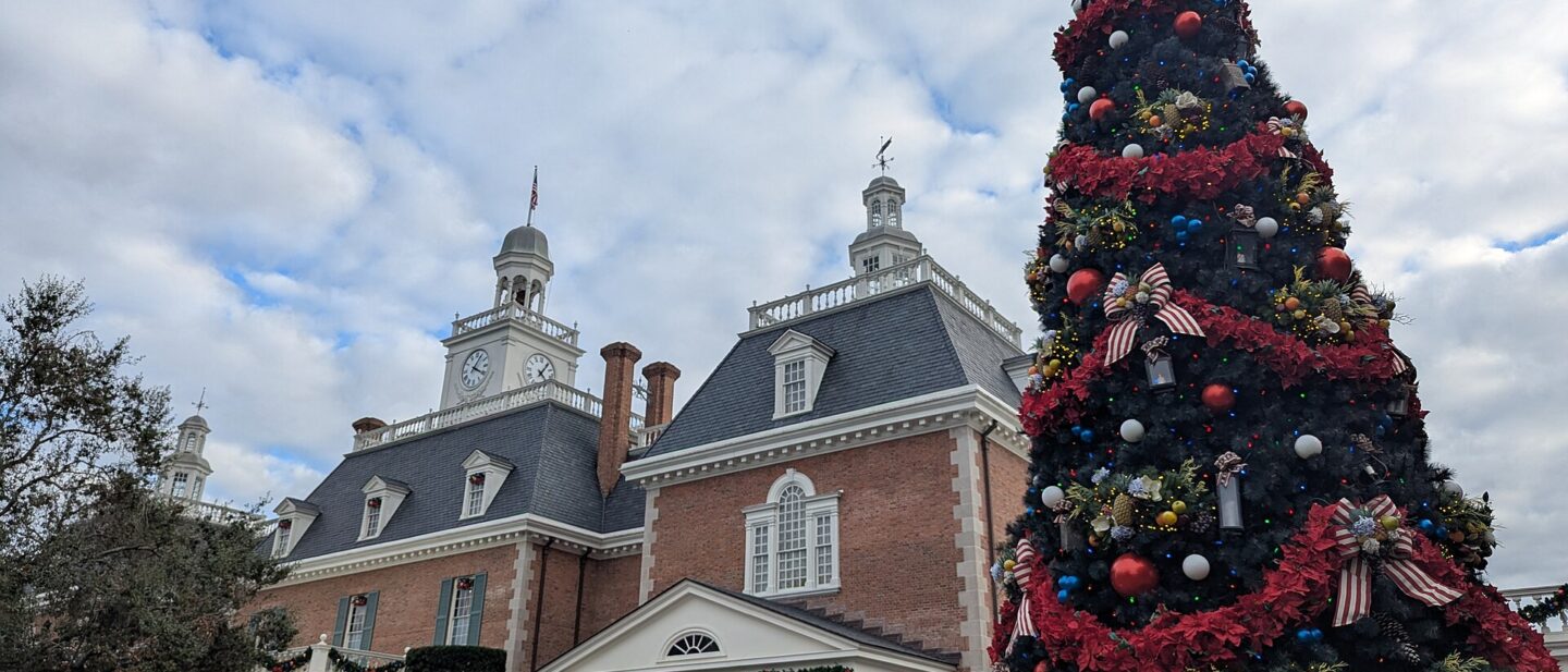 A tall decorated Christmas tree beside the American Adventure pavilion at EPCOT