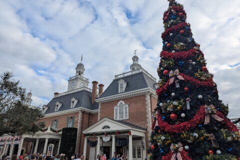 A tall decorated Christmas tree beside the American Adventure pavilion at EPCOT