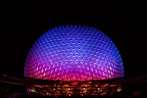 Spaceship Earth at EPCOT lit in purple, blue and pink against a black night sky