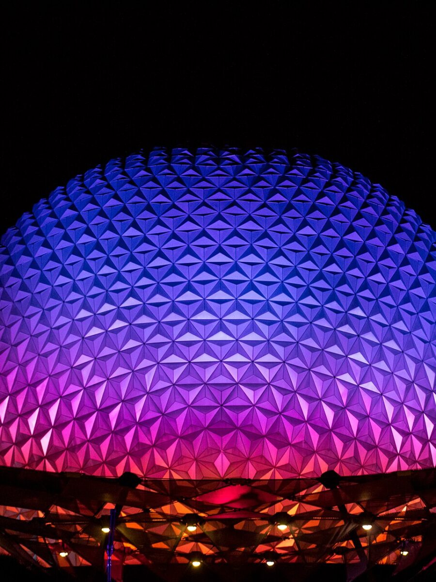 Spaceship Earth at EPCOT lit in purple, blue and pink against a black night sky