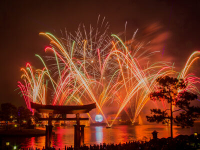 Fireworks exploding over World Showcase Lagoon at EPCOT, framed by the torii gate at the Japan pavilion