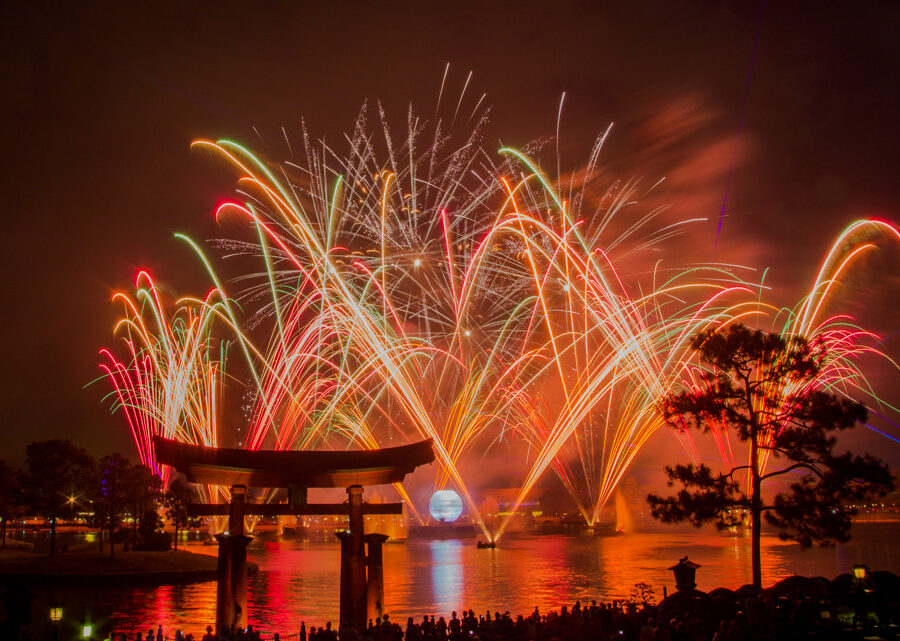 Fireworks exploding over World Showcase Lagoon at EPCOT, framed by the torii gate at the Japan pavilion