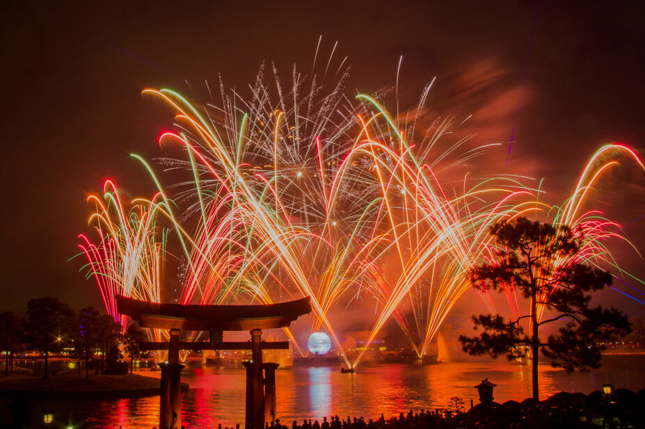 Fireworks exploding over World Showcase Lagoon at EPCOT, framed by the torii gate at the Japan pavilion