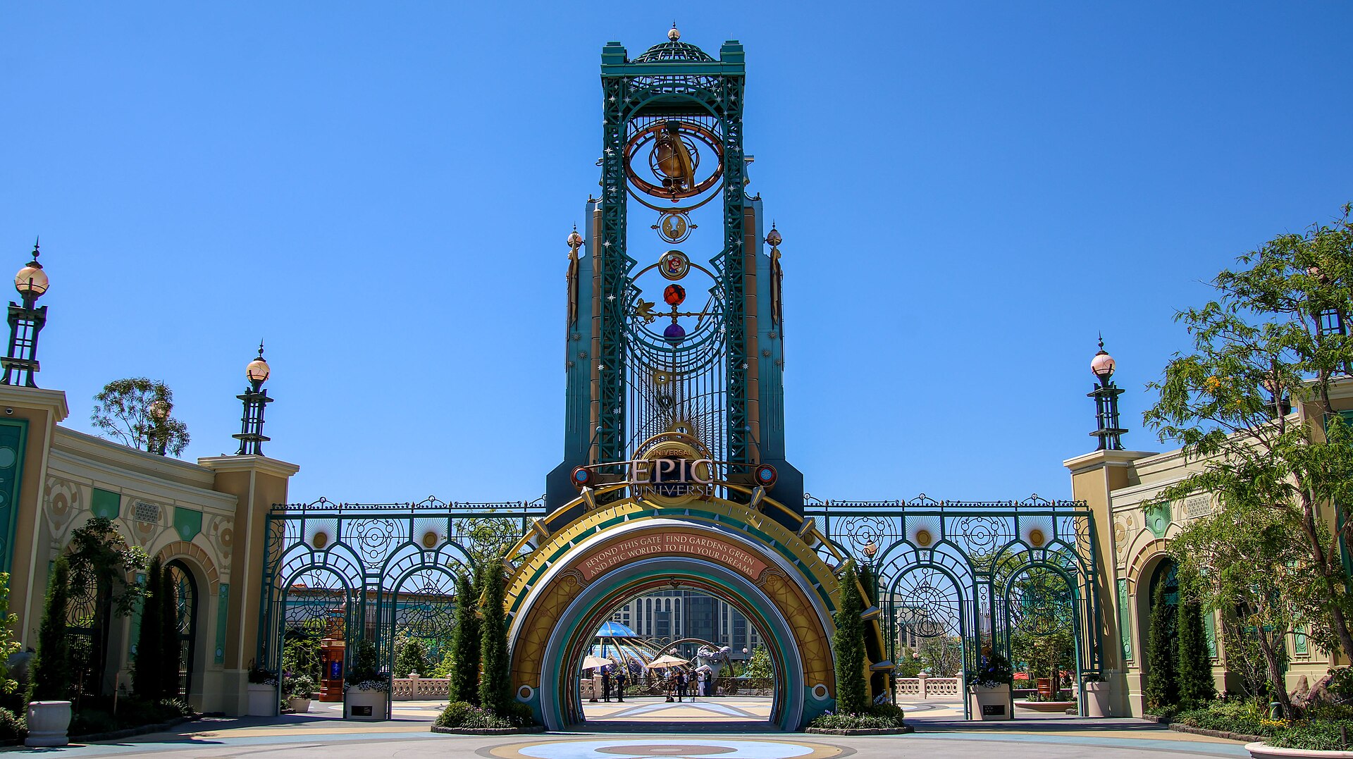 The Chronos tower and ornate green and gold gateway at the entrance to Epic Universe, with Celestial Park visible through the arch