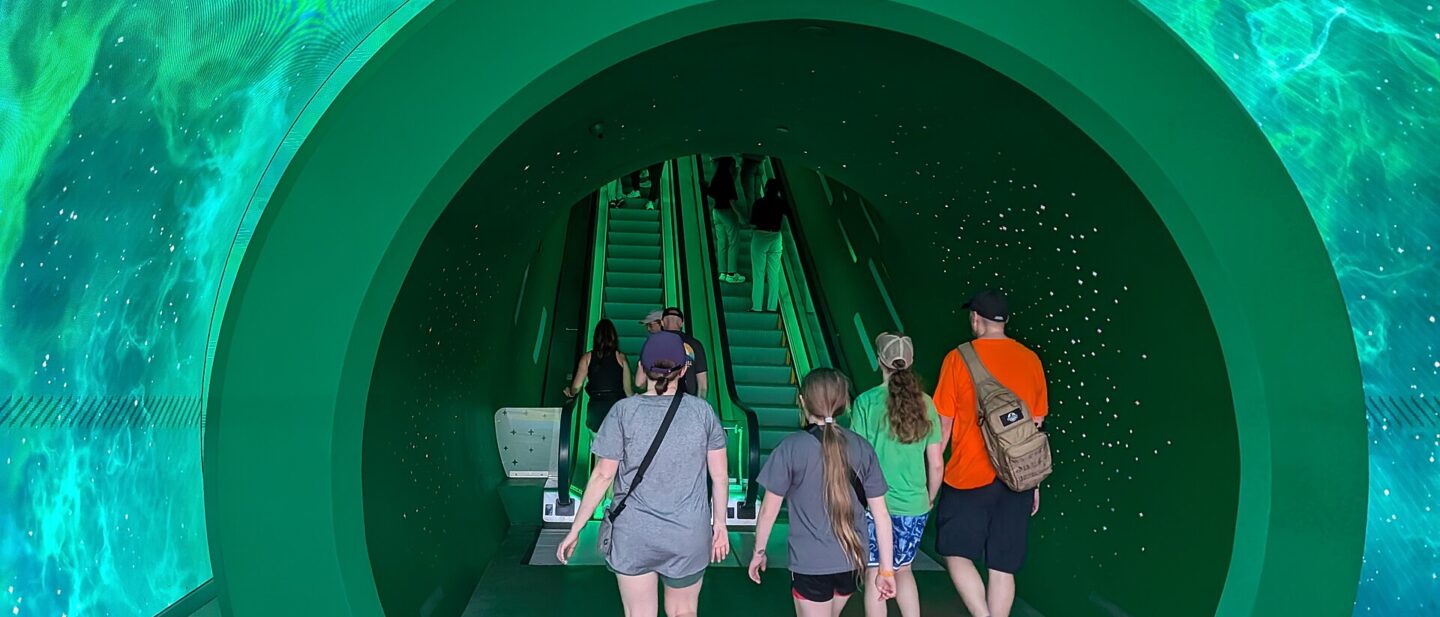 Visitors walking through the green warp-pipe portal tunnel into Super Nintendo World at Epic Universe, with starry projections overhead