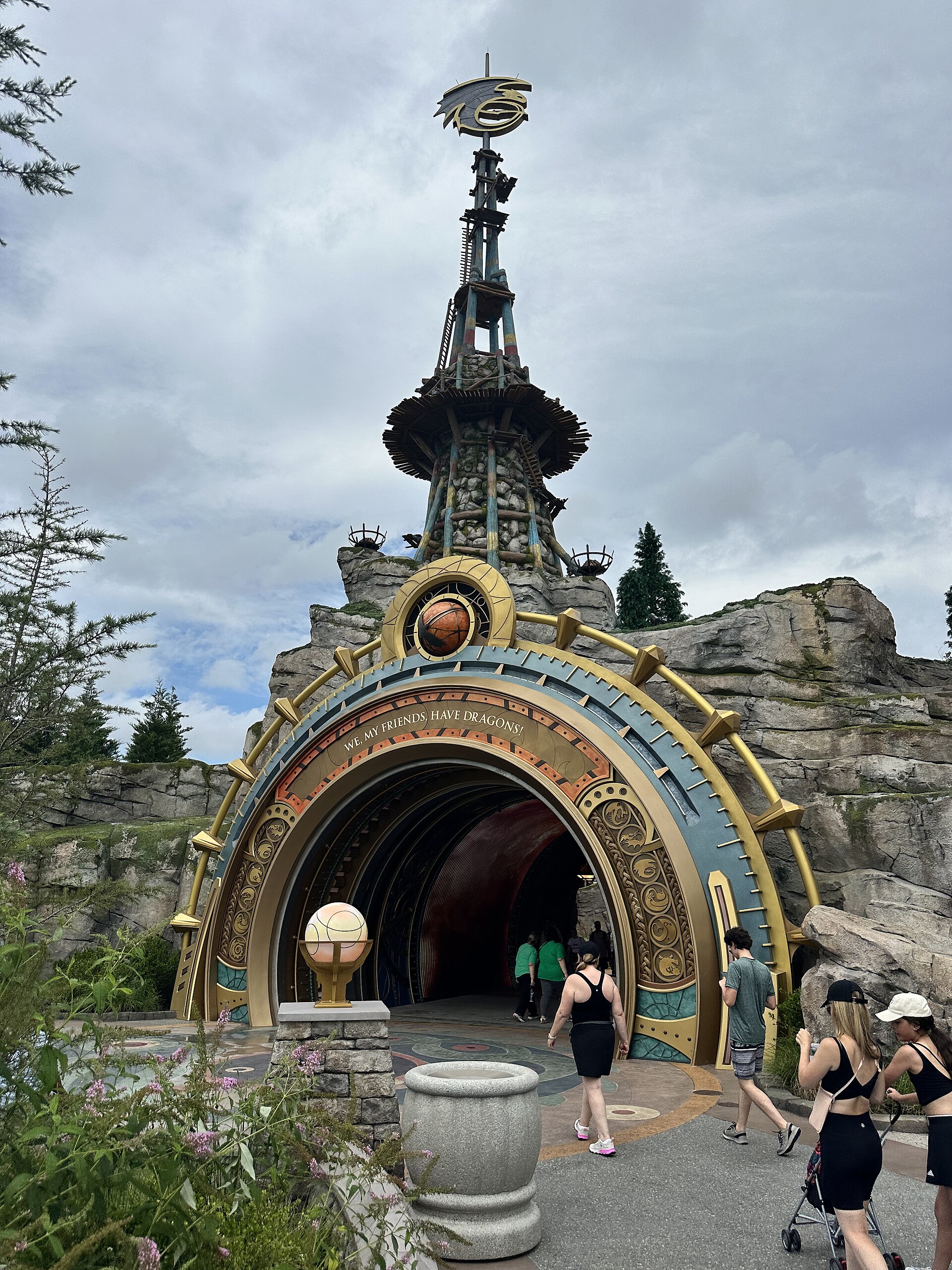 The gold and blue portal to How to Train Your Dragon – Isle of Berk at Epic Universe, inscribed We, my friends, have dragons, beneath a Viking watchtower