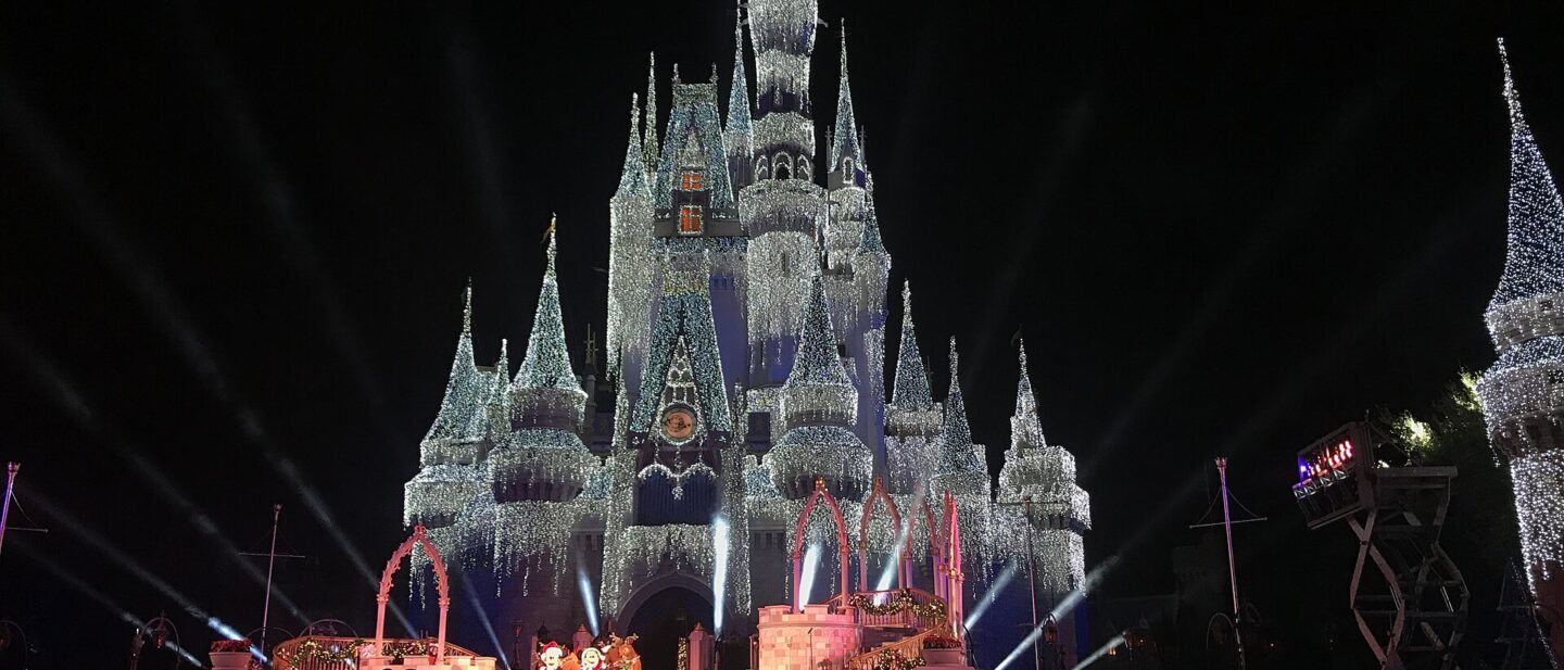 Cinderella Castle covered in lights at night with a stage show in front during a Magic Kingdom Christmas party