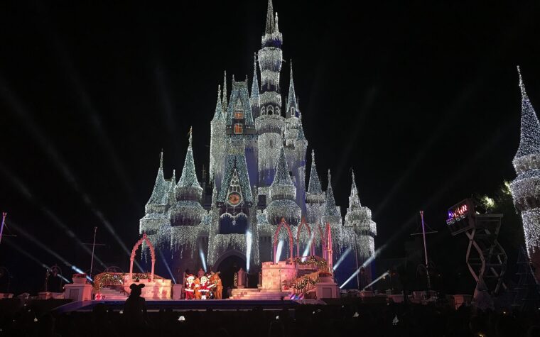 Cinderella Castle covered in lights at night with a stage show in front during a Magic Kingdom Christmas party