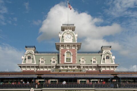 The Main Street Station building at the entrance to Magic Kingdom, with its clock tower and flagpole