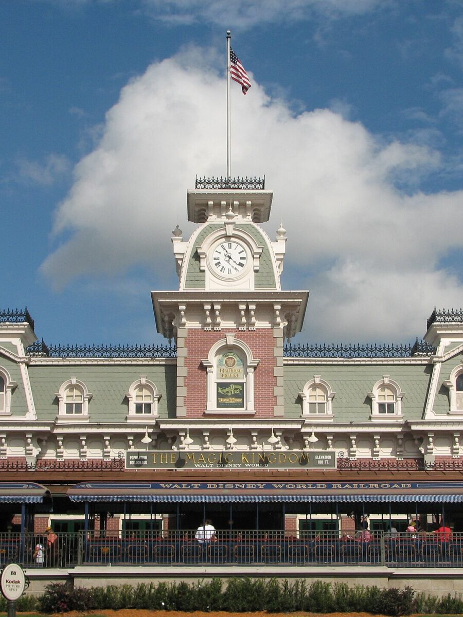 The Main Street Station building at the entrance to Magic Kingdom, with its clock tower and flagpole