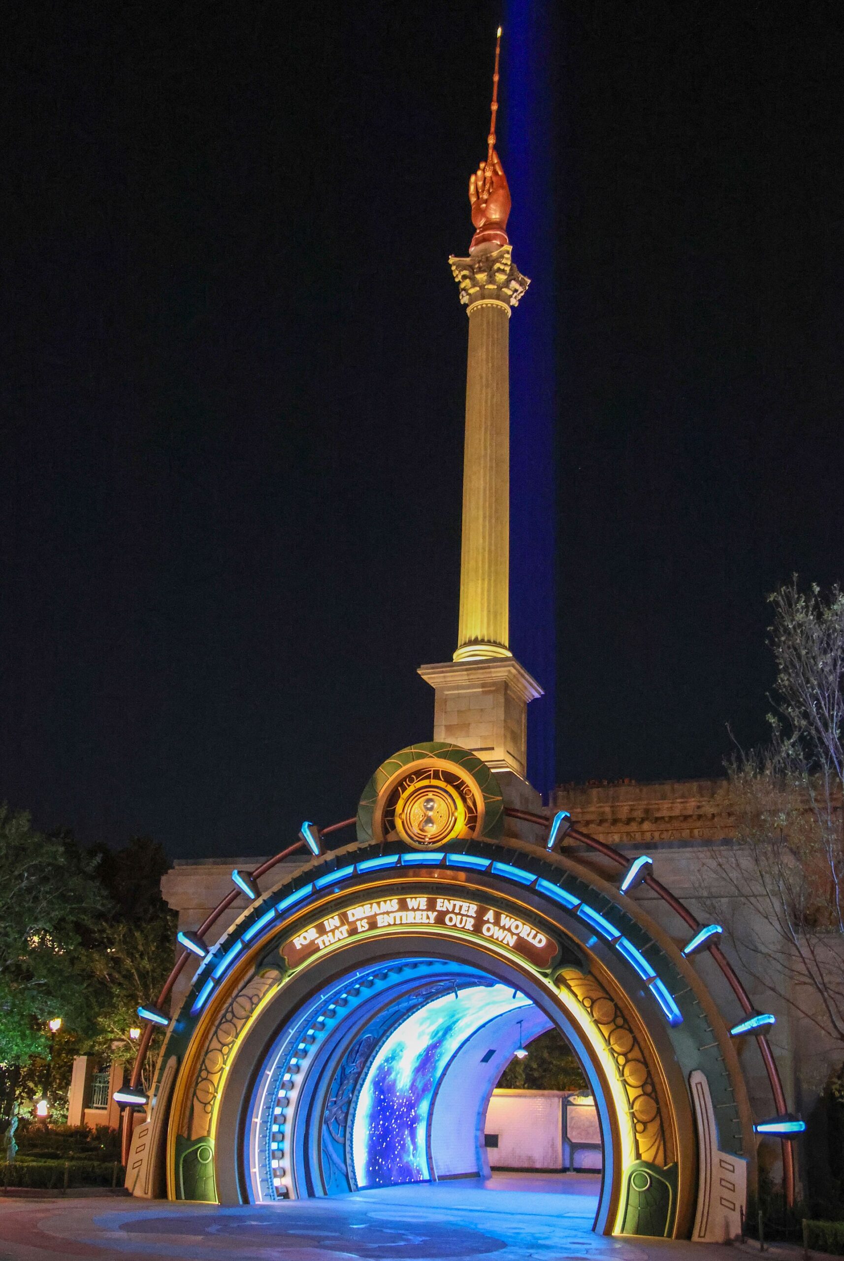 The illuminated portal to the Ministry of Magic at Epic Universe at night, an arch lit in blue and gold