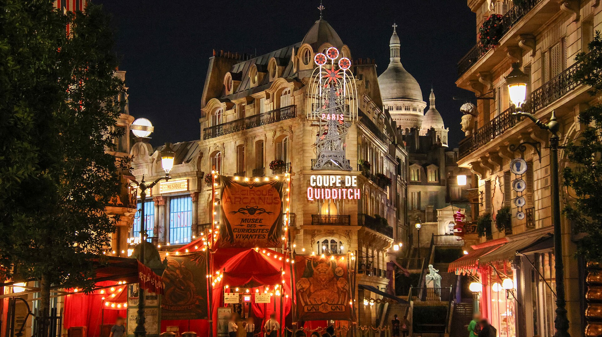 Place Cachée at night, with the red Le Cirque Arcanus tent strung with lights, a neon Eiffel Tower sign reading Coupe de Quidditch, and a domed church on the skyline