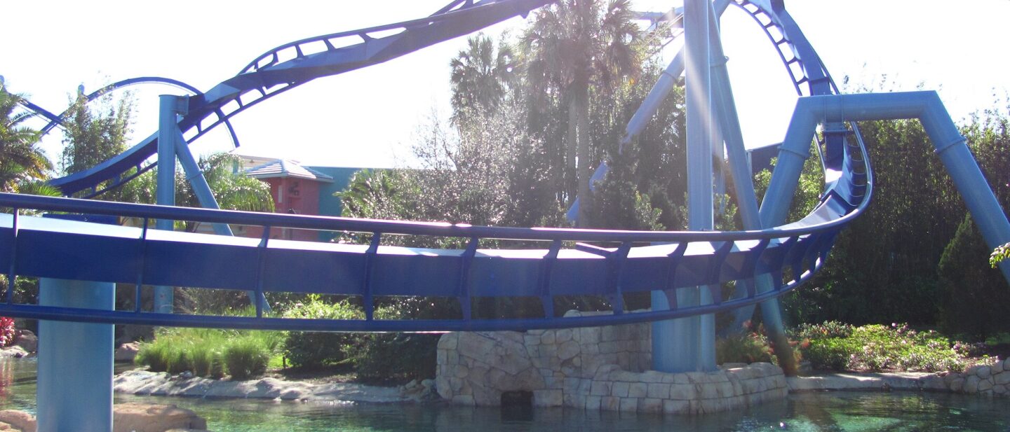 Blue track of the Manta flying coaster curving low over a clear lagoon at SeaWorld Orlando