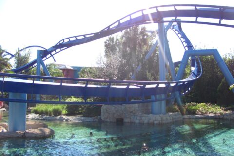 Blue track of the Manta flying coaster curving low over a clear lagoon at SeaWorld Orlando