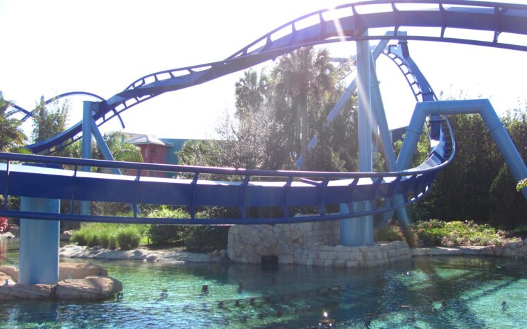 Blue track of the Manta flying coaster curving low over a clear lagoon at SeaWorld Orlando