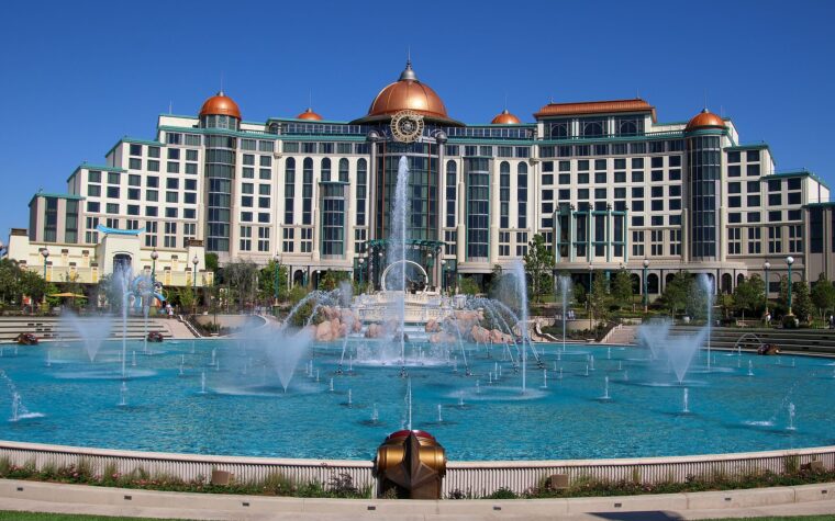 Universal Helios Grand Hotel, a large cream building with copper domes, seen across the dancing fountains of Celestial Park