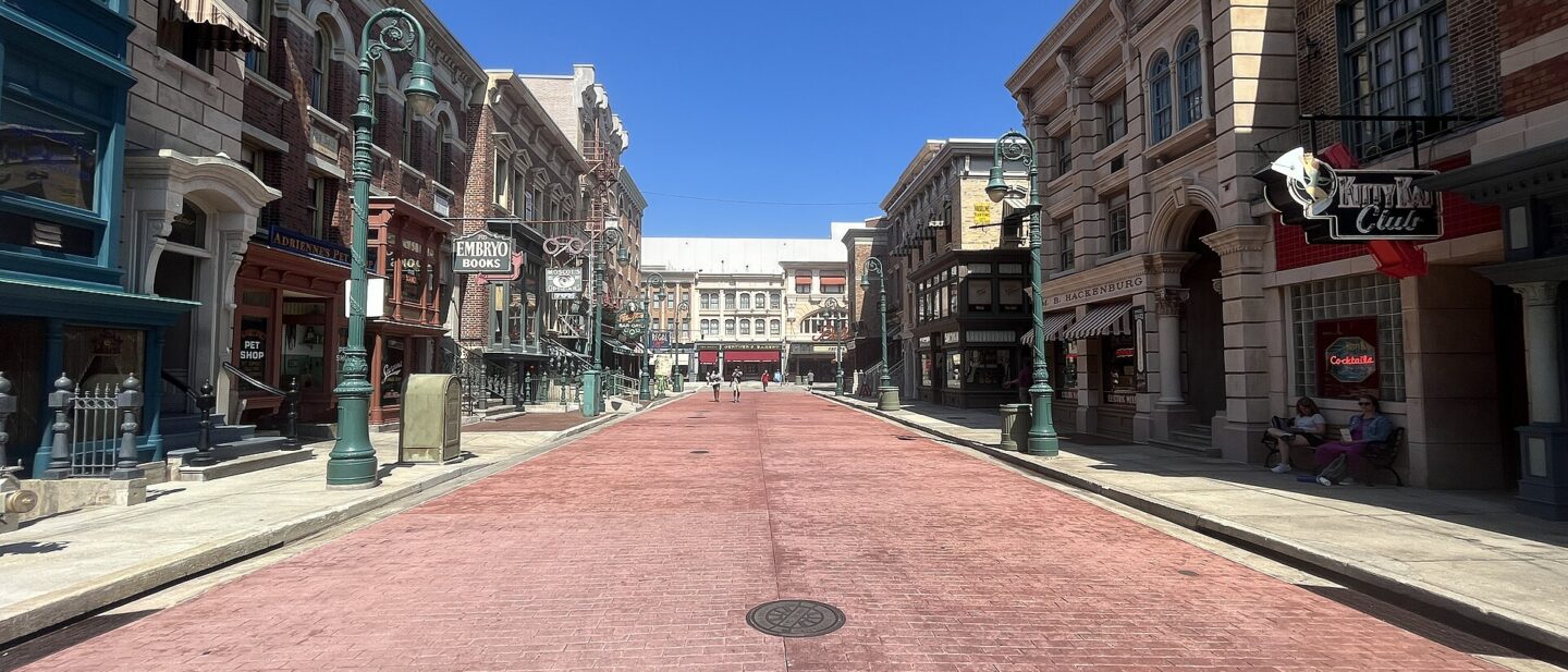 Delancey Street at Universal Studios Florida, a wide brick-paved street lined with New York style shopfronts under a clear blue sky