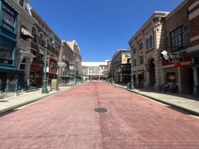 Delancey Street at Universal Studios Florida, a wide brick-paved street lined with New York style shopfronts under a clear blue sky