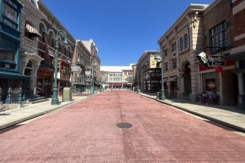 Delancey Street at Universal Studios Florida, a wide brick-paved street lined with New York style shopfronts under a clear blue sky