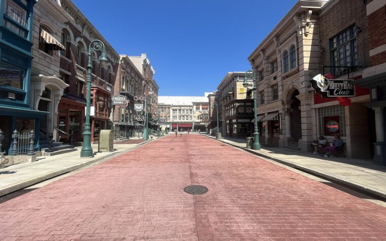 Delancey Street at Universal Studios Florida, a wide brick-paved street lined with New York style shopfronts under a clear blue sky