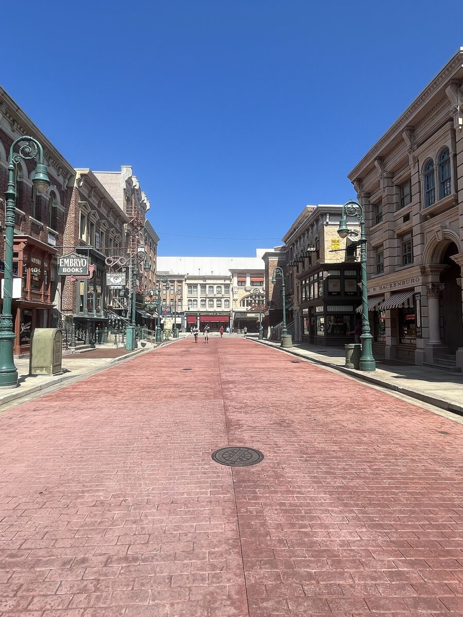 Delancey Street at Universal Studios Florida, a wide brick-paved street lined with New York style shopfronts under a clear blue sky