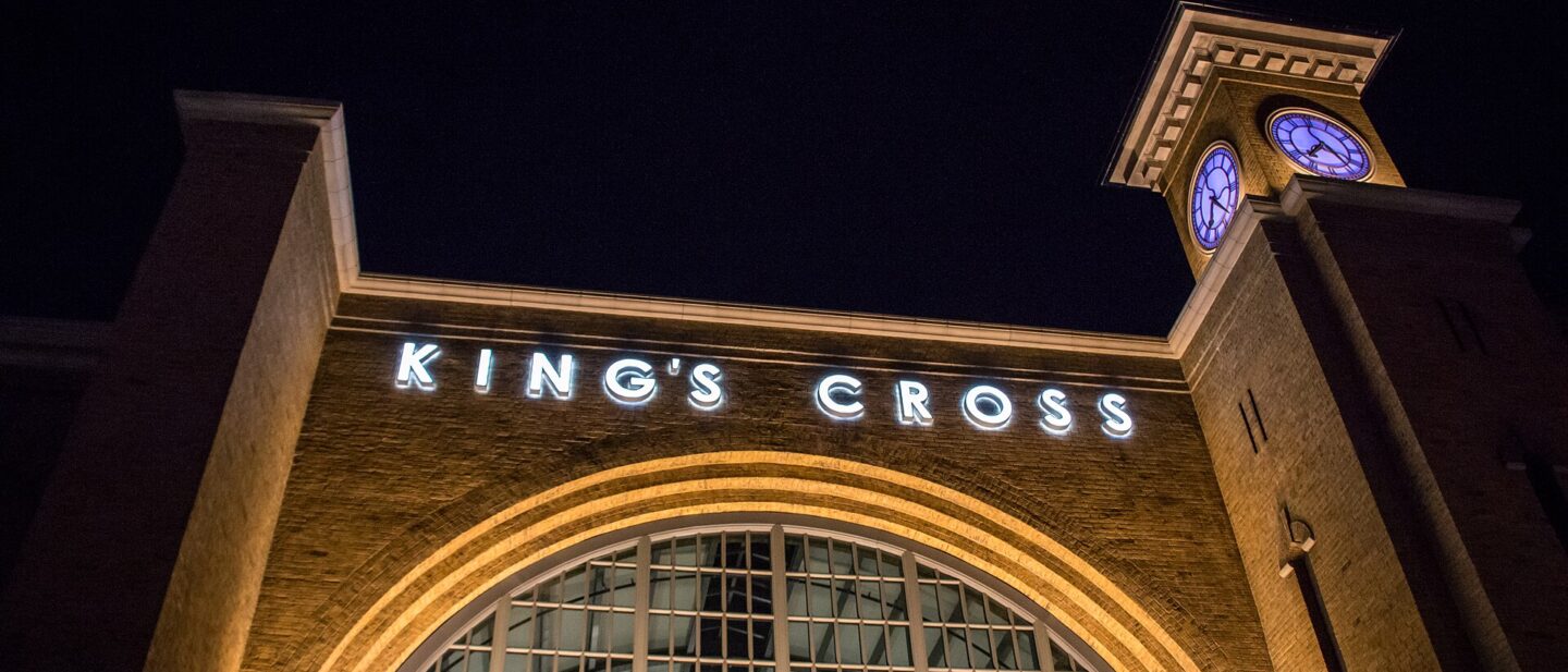 The King's Cross station facade at Universal Studios Florida lit up at night, with its arched window and clock tower