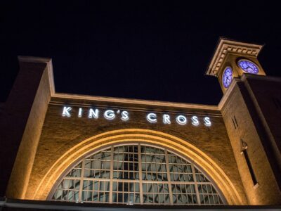 The King's Cross station facade at Universal Studios Florida lit up at night, with its arched window and clock tower