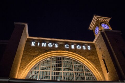The King's Cross station facade at Universal Studios Florida lit up at night, with its arched window and clock tower
