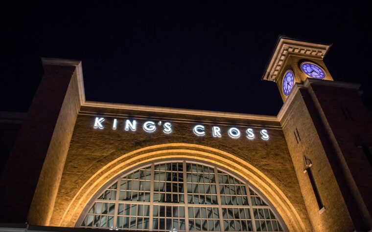 The King's Cross station facade at Universal Studios Florida lit up at night, with its arched window and clock tower