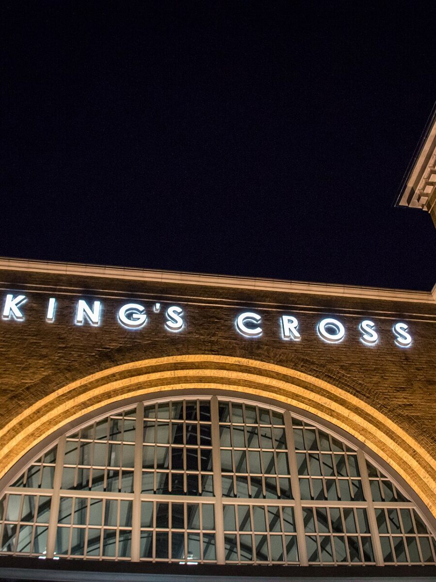 The King's Cross station facade at Universal Studios Florida lit up at night, with its arched window and clock tower