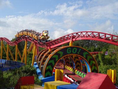 A Slinky Dog Dash train full of riders with raised arms on the red and yellow track in Toy Story Land at Hollywood Studios